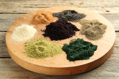 Different superfood powders on wooden table, closeup