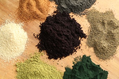 Photo of Different superfood powders on wooden table, flat lay