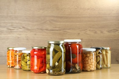 Photo of Different pickled products in jars on wooden table