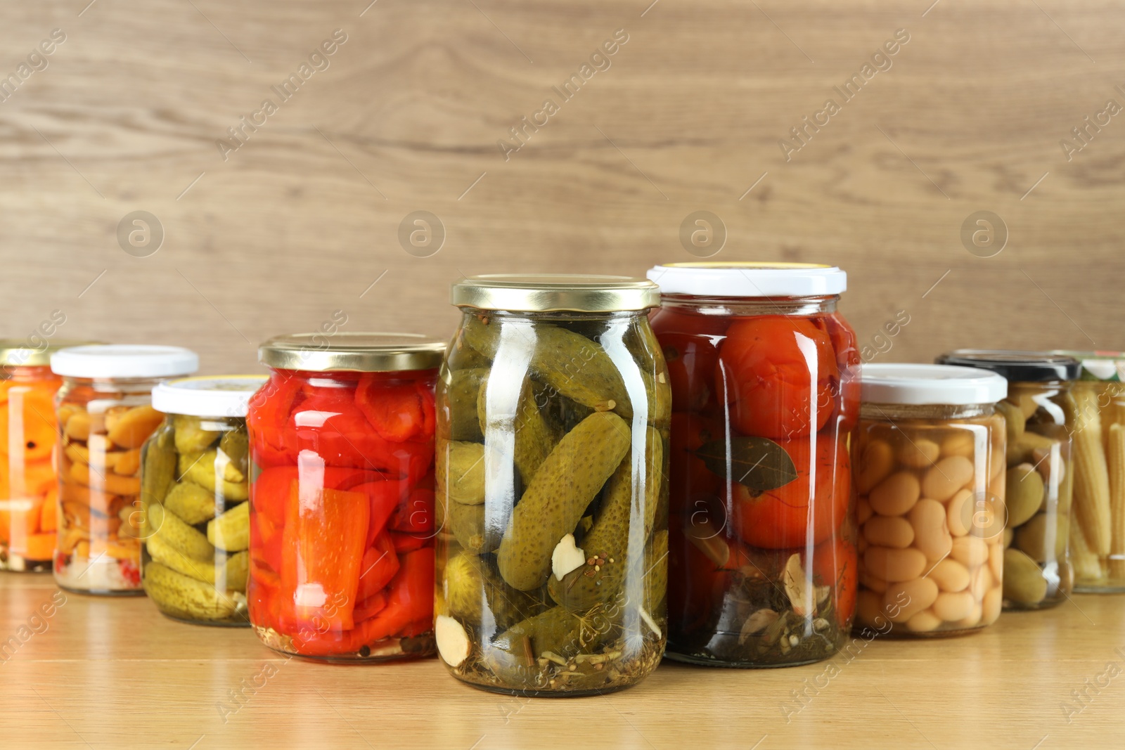 Photo of Different pickled products in jars on wooden table