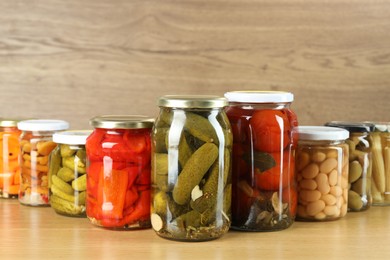 Photo of Different pickled products in jars on wooden table