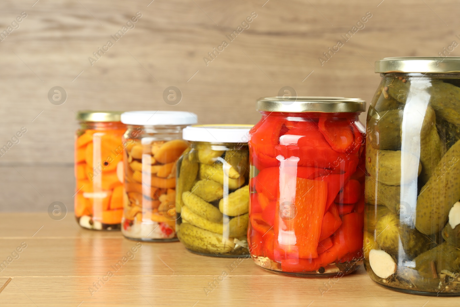 Photo of Different pickled products in jars on wooden table