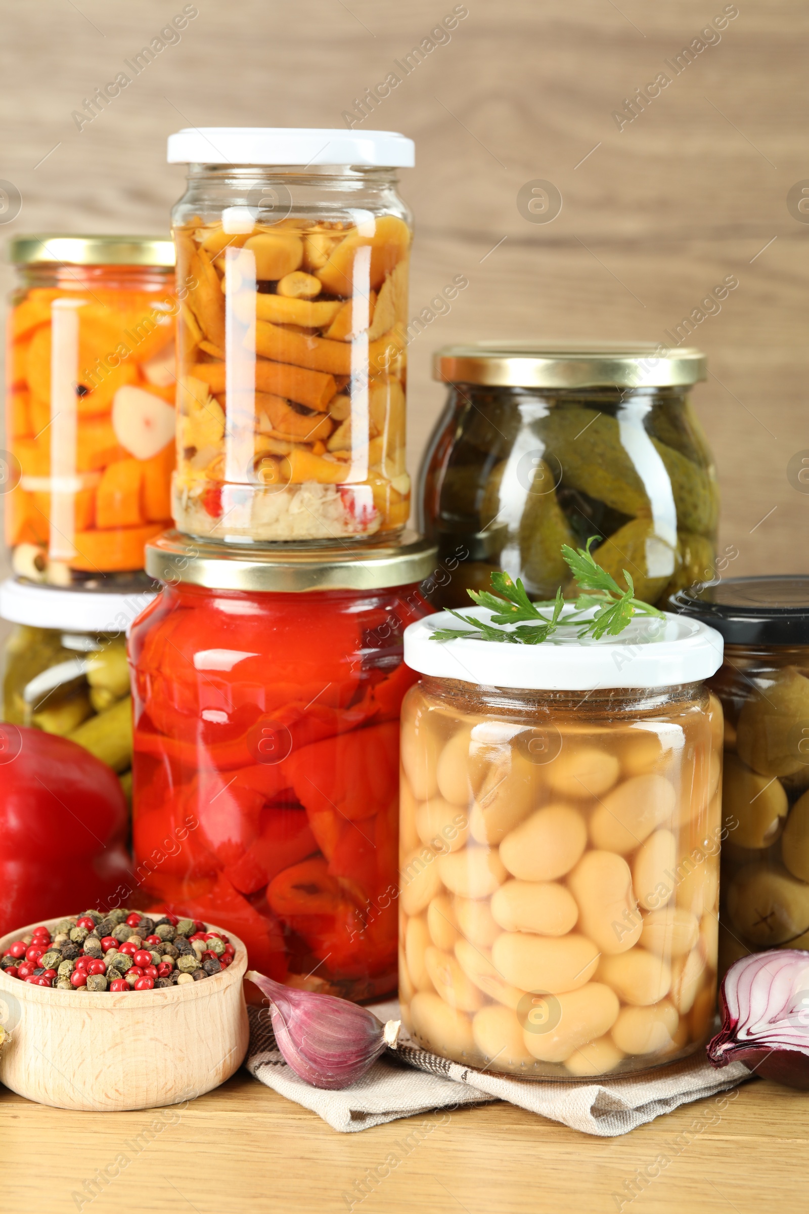 Photo of Different pickled products in jars and spices on wooden table