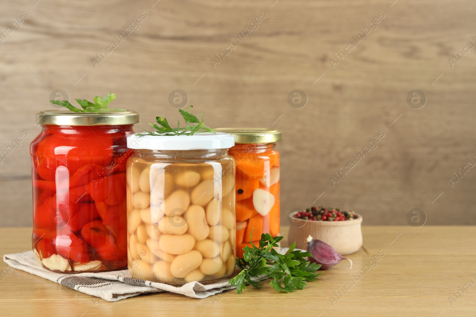 Photo of Different pickled products in jars and spices on wooden table