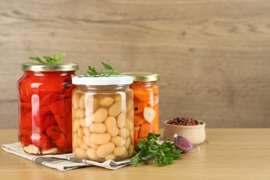 Photo of Different pickled products in jars and spices on wooden table