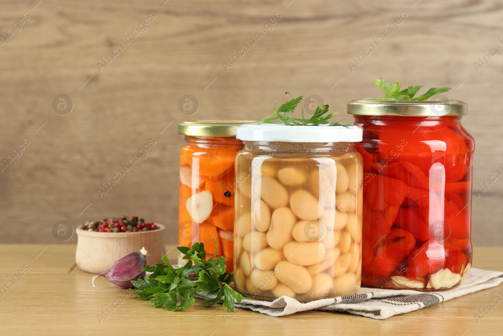 Photo of Different pickled products in jars and spices on wooden table