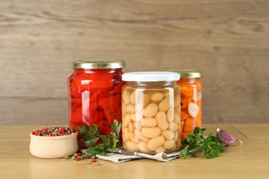 Photo of Different pickled products in jars and spices on wooden table