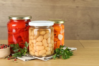 Photo of Different pickled products in jars and spices on wooden table