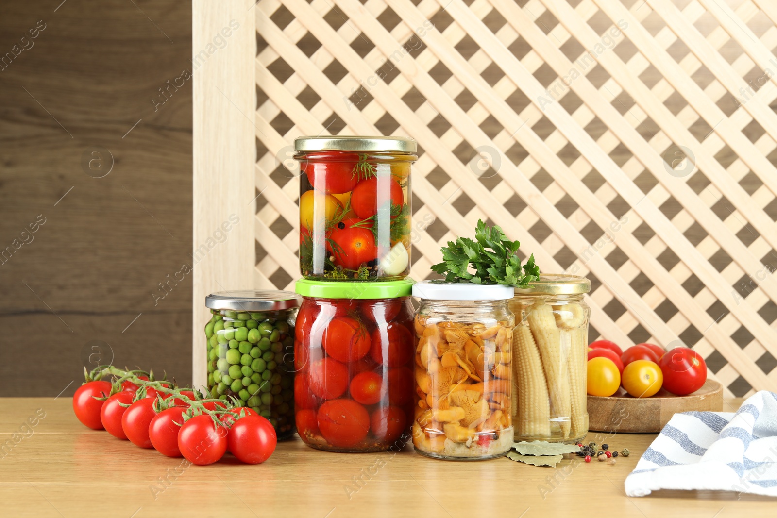 Photo of Different pickled products in jars, fresh tomatoes and spices on wooden table