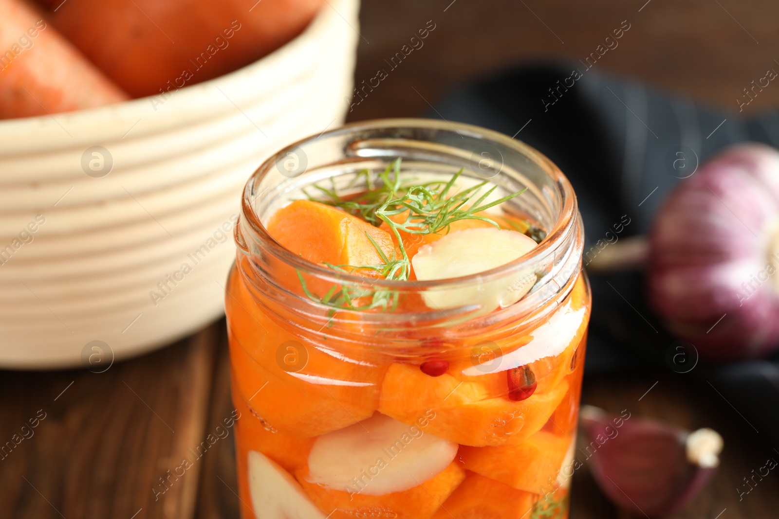 Photo of Tasty pickled carrots, garlic and dill in jar on table, closeup