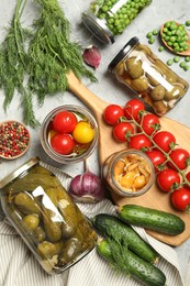 Photo of Different pickled products in jars and fresh ingredients on grey table, flat lay