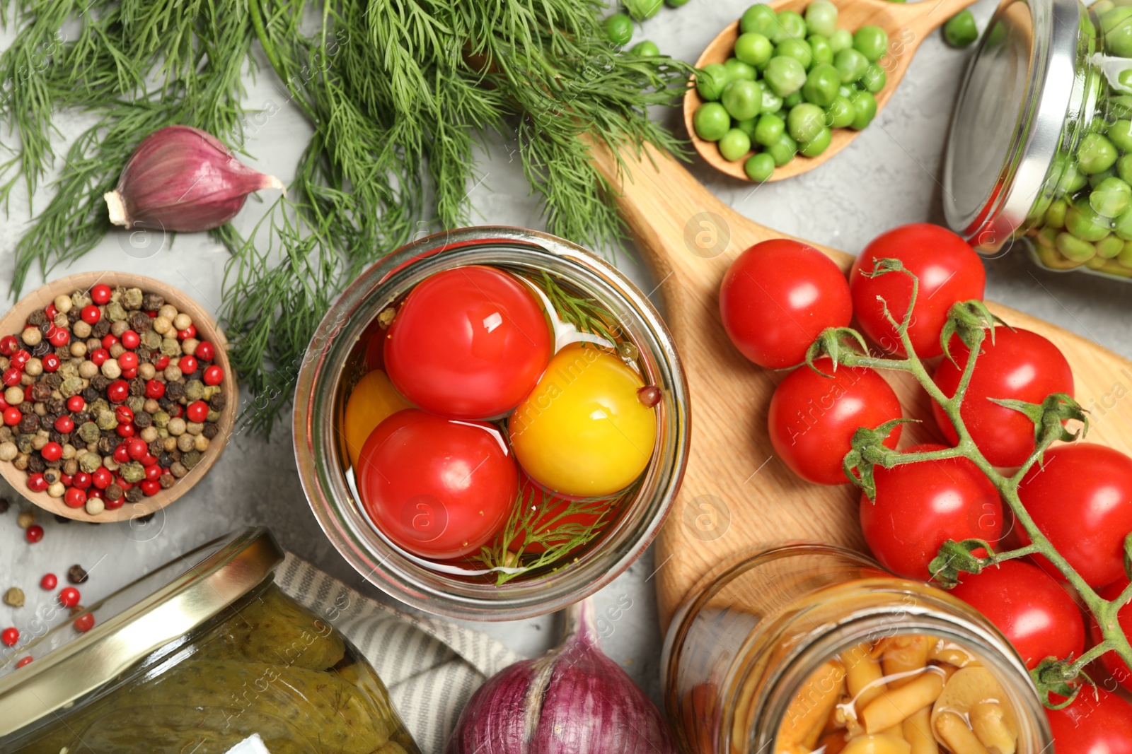 Photo of Different pickled products in jars and fresh ingredients on grey table, flat lay