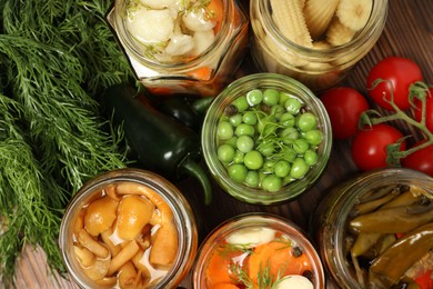 Photo of Different pickled products in jars and fresh ingredients on wooden table, flat lay