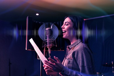 Image of Young singer with microphone recording song in studio, color toned. Audio waveform near her