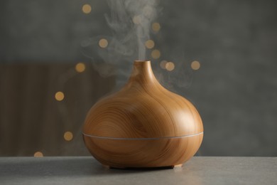 Aroma oil diffuser with steam on light grey table