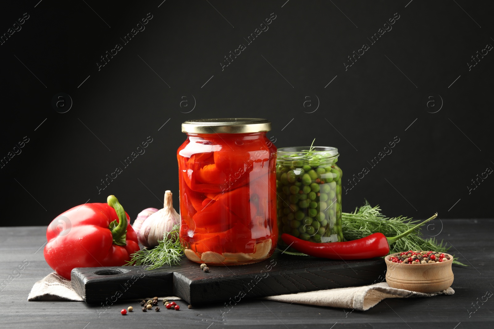 Photo of Different pickled products in jars and fresh ingredients on grey wooden table