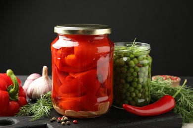 Photo of Different pickled products in jars and fresh ingredients on table, closeup