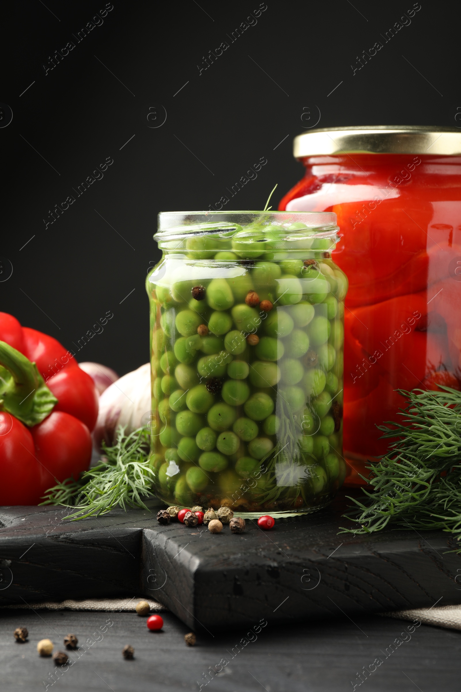 Photo of Different pickled products in jars and fresh ingredients on grey wooden table