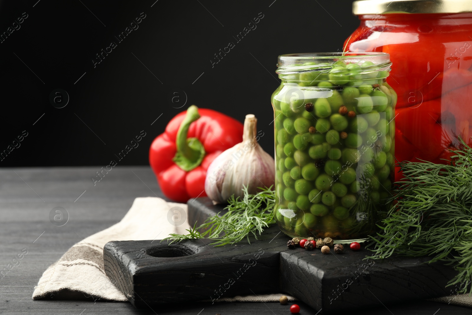 Photo of Different pickled products in jars and fresh ingredients on grey wooden table