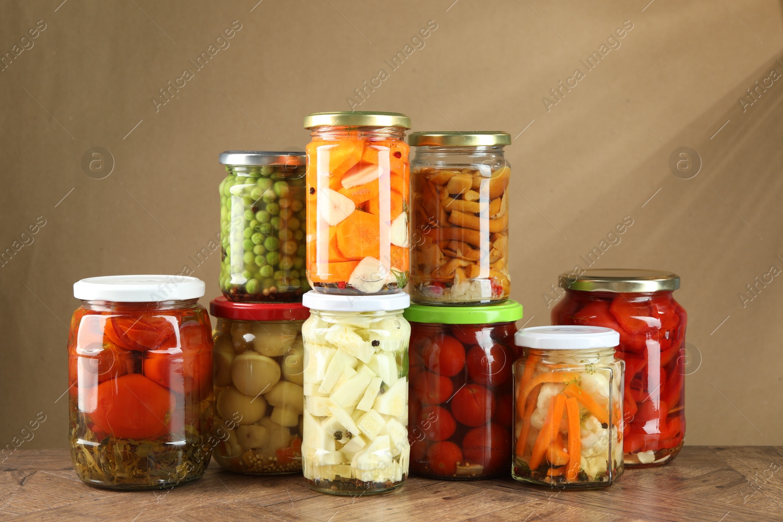 Photo of Different pickled products in jars on wooden table