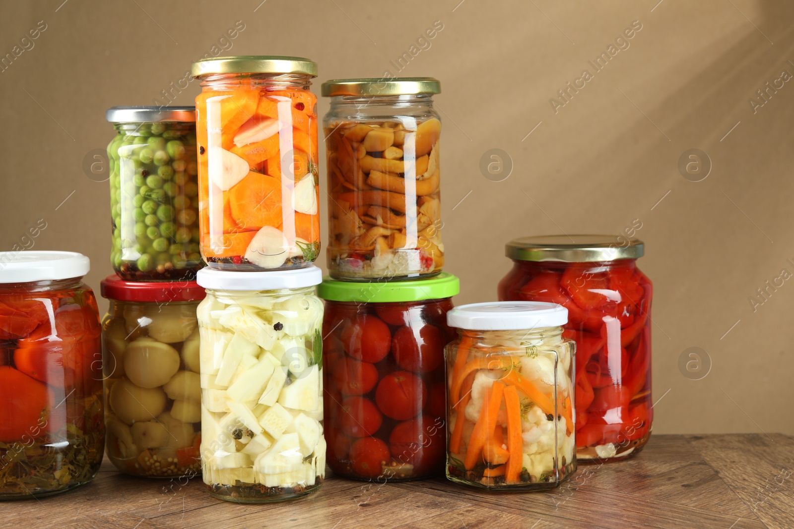 Photo of Different pickled products in jars on wooden table