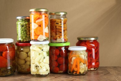 Photo of Different pickled products in jars on wooden table