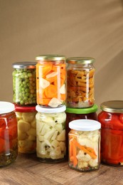 Photo of Different pickled products in jars on wooden table