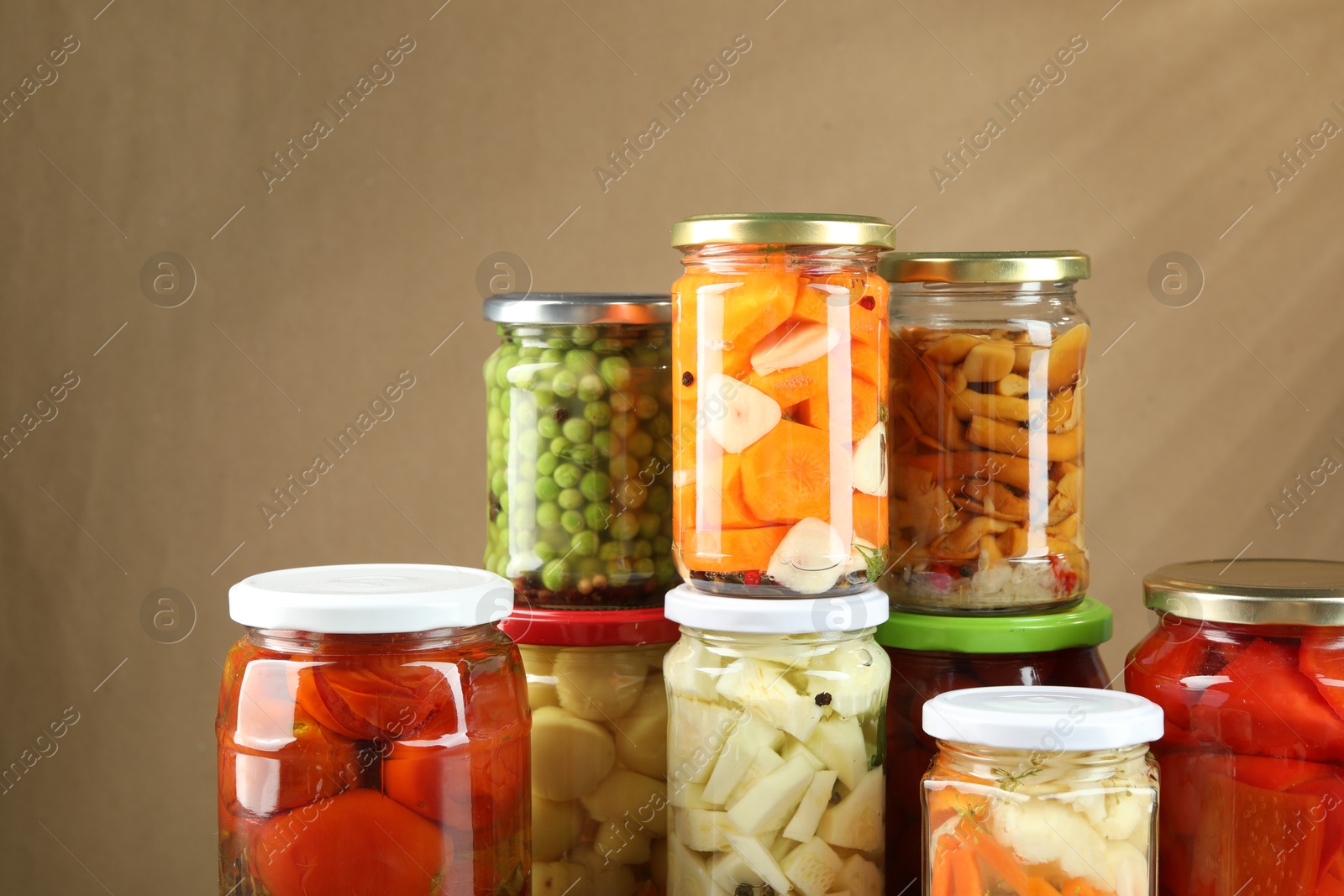 Photo of Different pickled products in jars on beige background