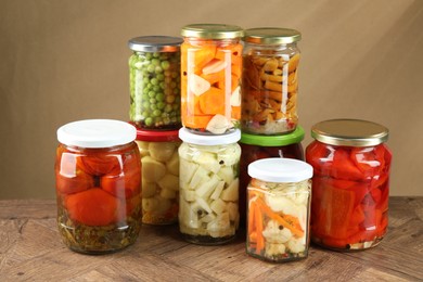 Photo of Different pickled products in jars on wooden table