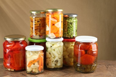 Photo of Different pickled products in jars on wooden table