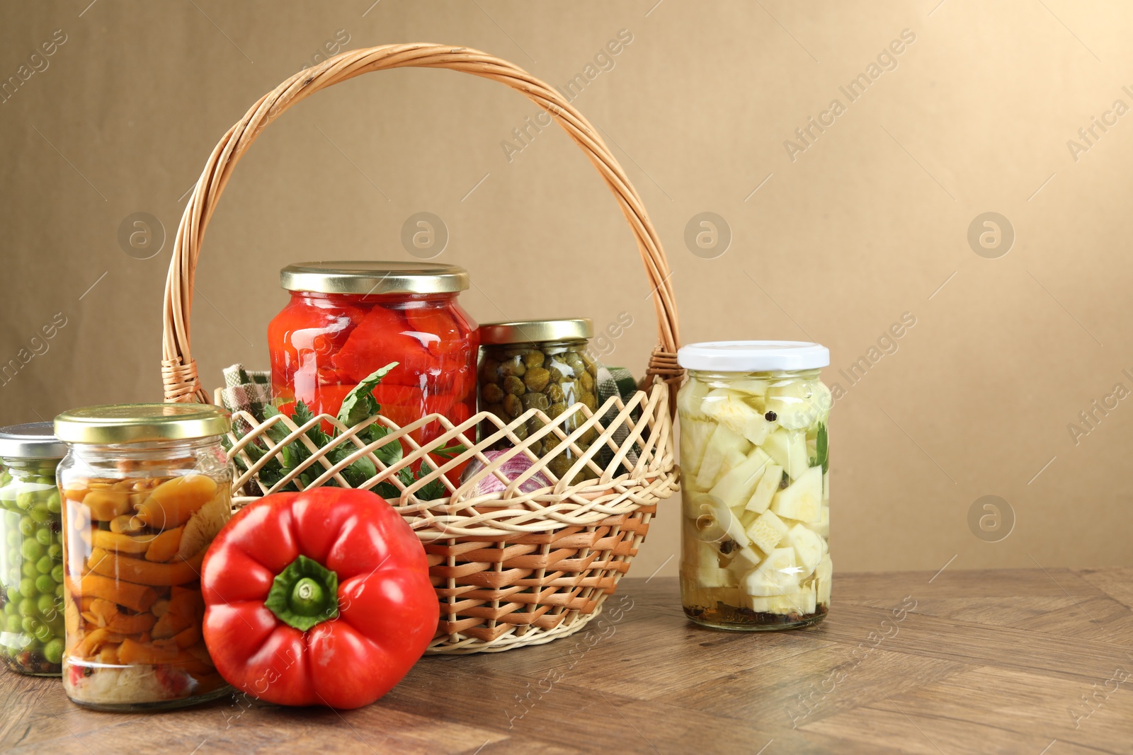 Photo of Different pickled products in jars and fresh ingredients on wooden table