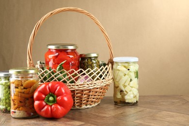 Photo of Different pickled products in jars and fresh ingredients on wooden table