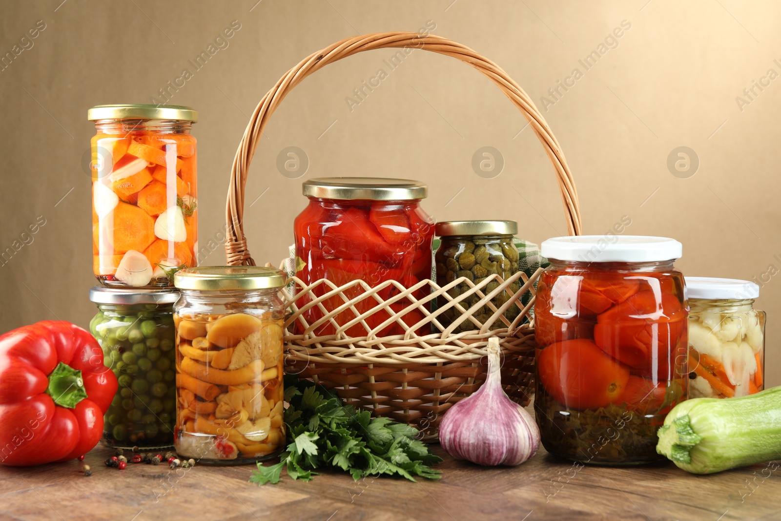 Photo of Different pickled products in jars and fresh ingredients on wooden table