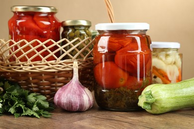 Photo of Different pickled products in jars and fresh ingredients on wooden table, closeup