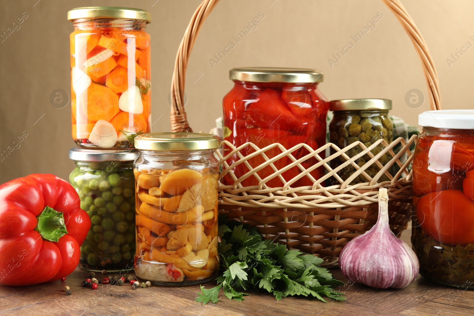 Photo of Different pickled products in jars and fresh ingredients on wooden table