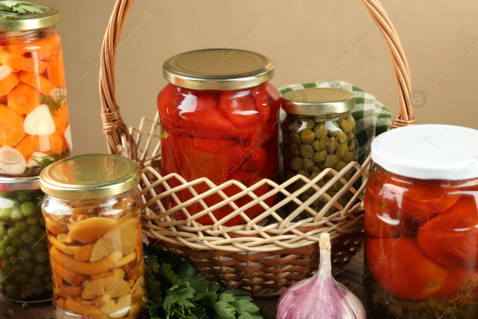 Photo of Different pickled products in jars, parsley and garlic on table, closeup