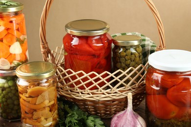 Photo of Different pickled products in jars, parsley and garlic on table, closeup