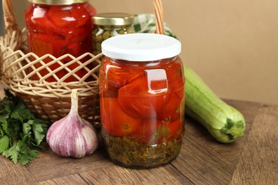 Photo of Different pickled products in jars and fresh ingredients on wooden table