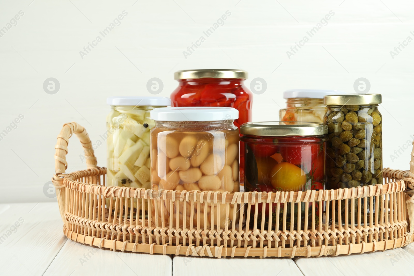 Photo of Different pickled products in jars on white wooden table