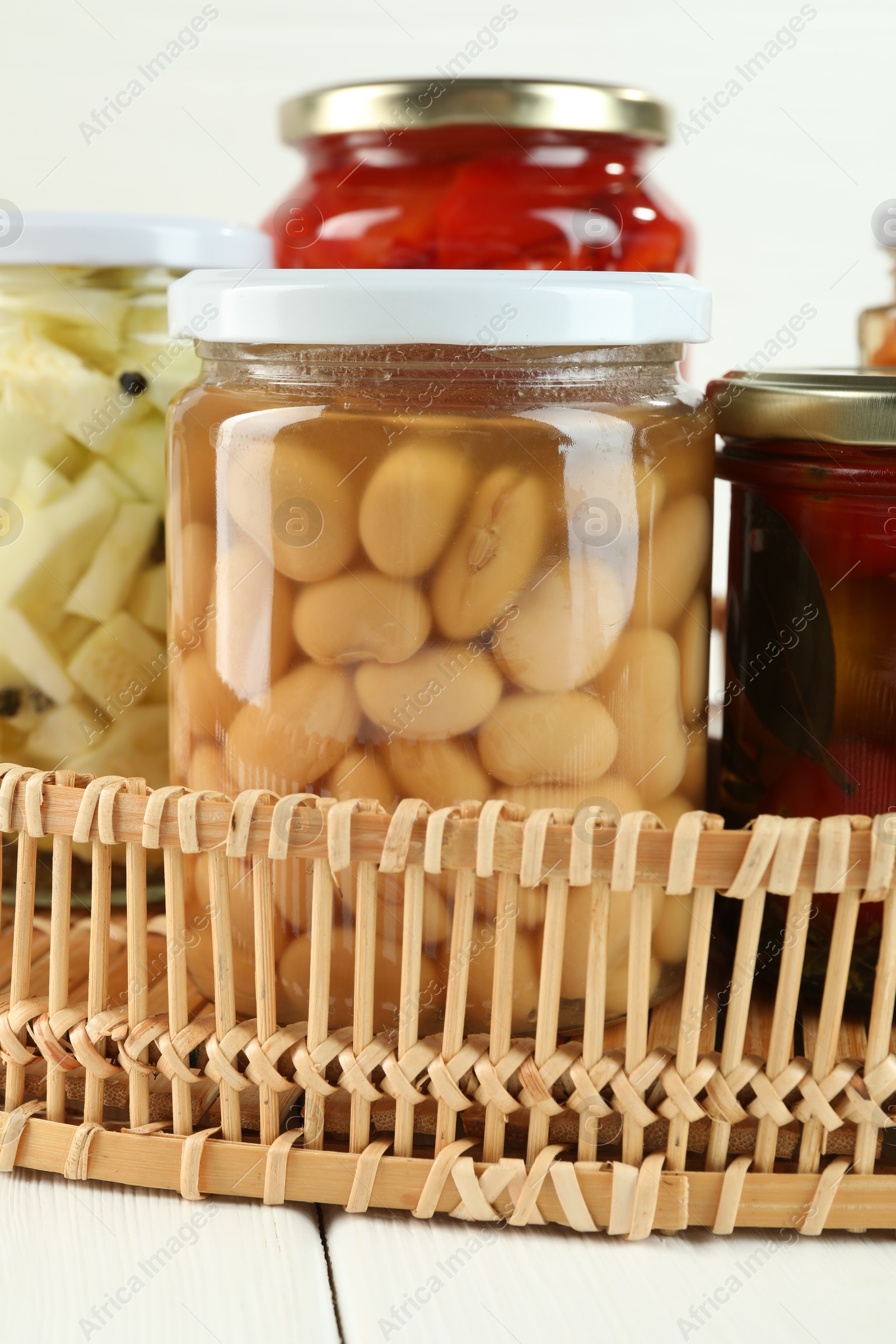 Photo of Different pickled products in jars on white wooden table, closeup