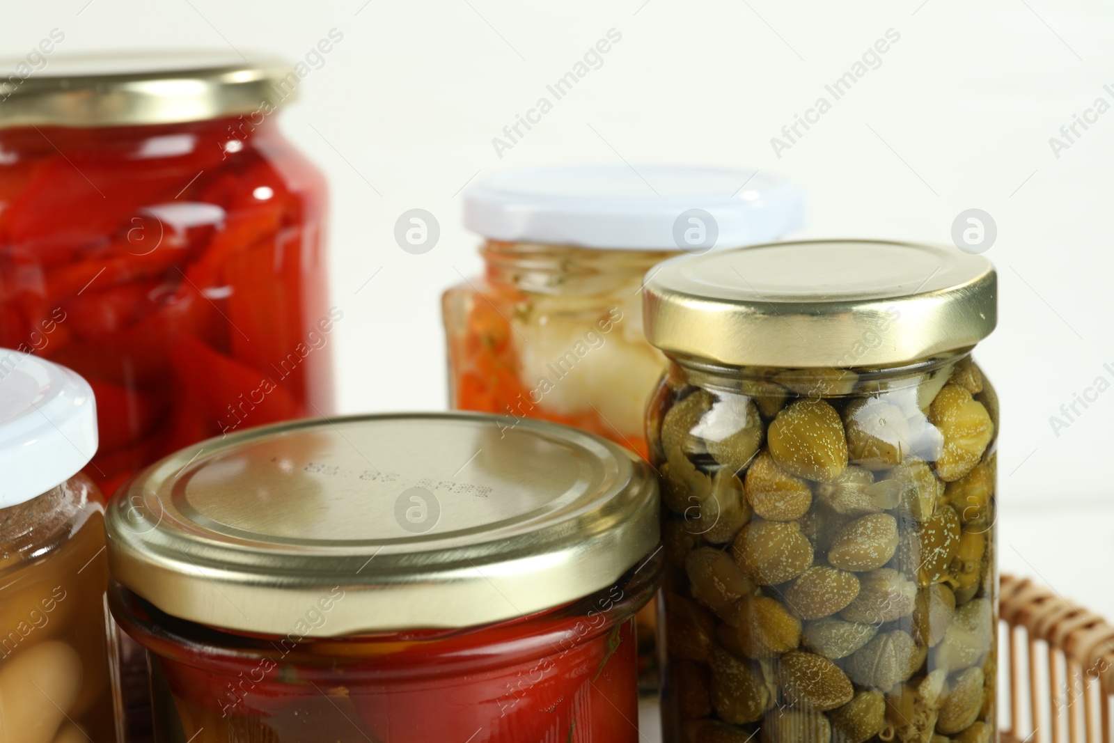 Photo of Different pickled products in jars on white background, closeup