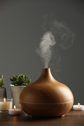 Aroma oil diffuser, houseplants and burning candles on wooden table