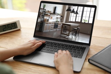 Woman looking for house on real estate market website at table, closeup