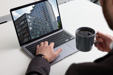 Image of Man looking for house on real estate market website at table, closeup