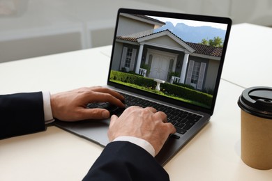 Image of Man looking for house on real estate market website at table, closeup