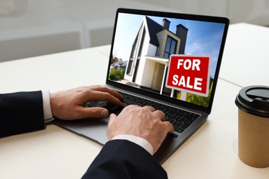 Image of Man looking for house on real estate market website at table, closeup