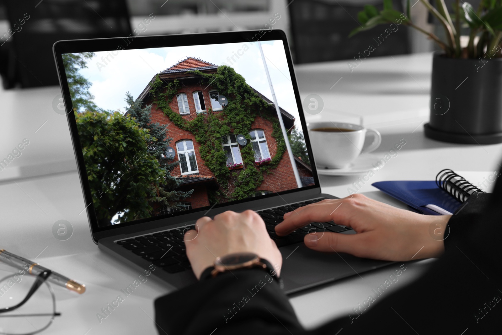 Image of Woman looking for house on real estate market website at table, closeup