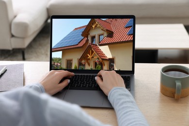 Image of Woman looking for house on real estate market website at table, closeup