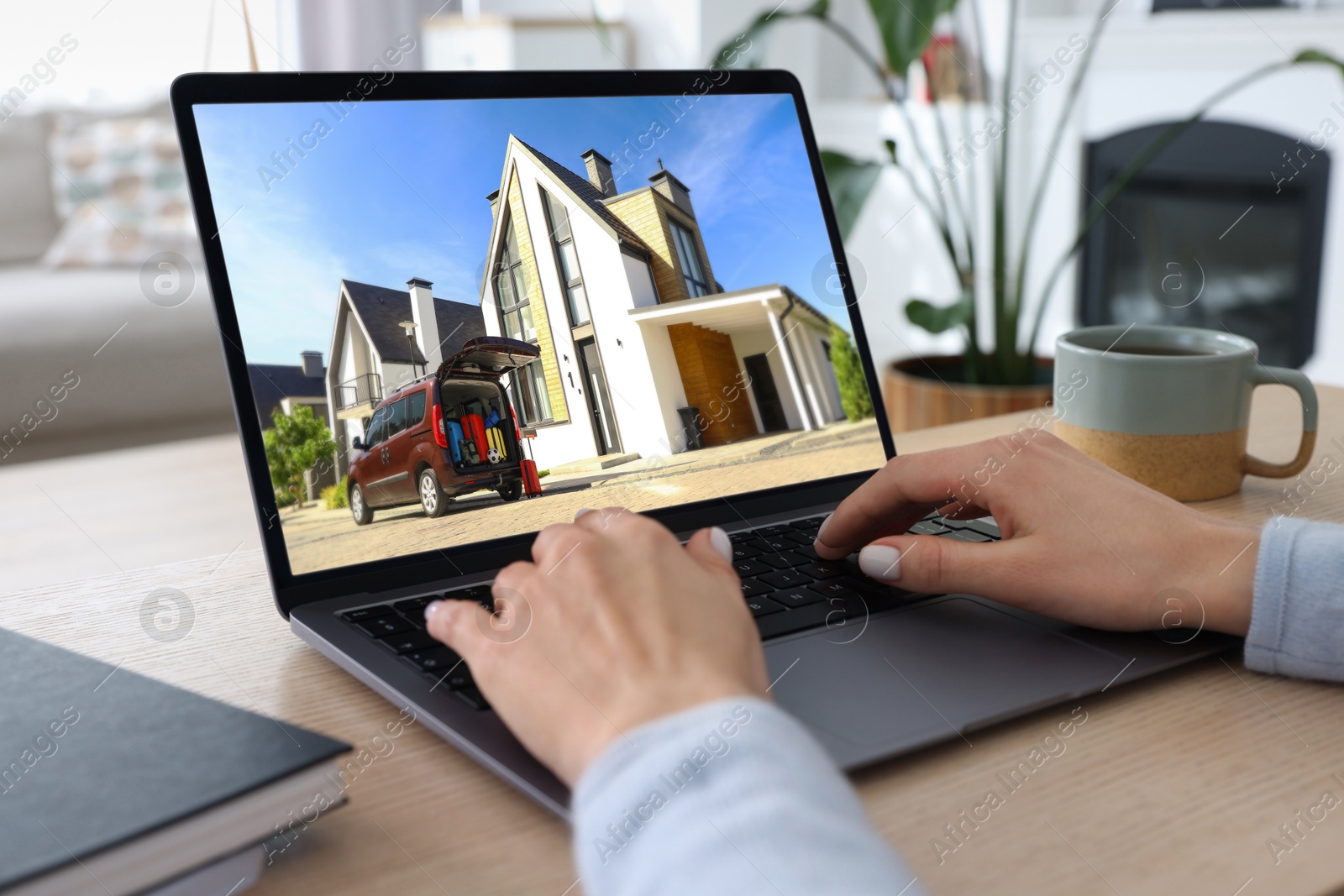 Image of Woman looking for house on real estate market website at table, closeup