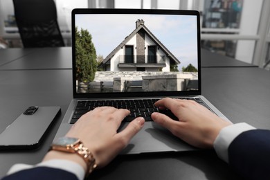 Woman looking for house on real estate market website at table, closeup